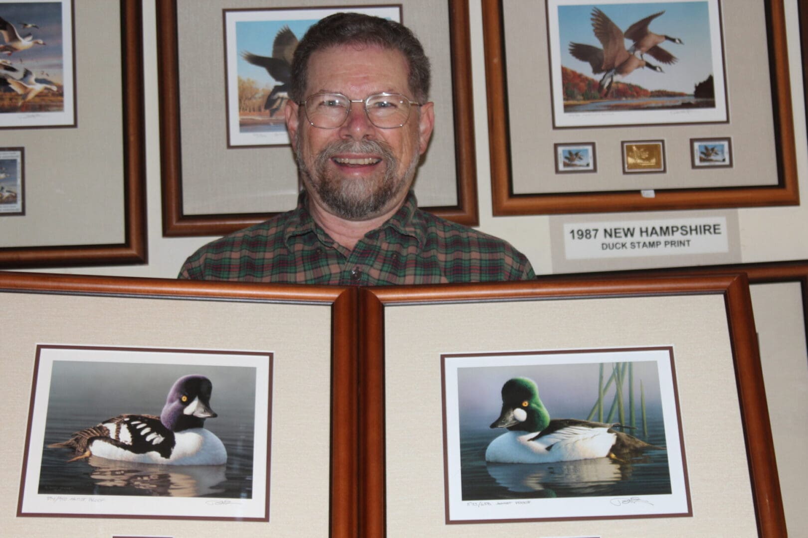 A man sitting in front of two framed pictures.